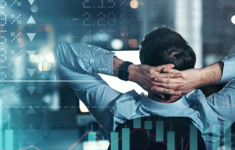 Photo of a person from behind leaning back in a chair holding their head watching their computer screen