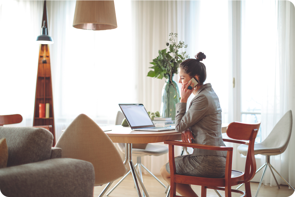 Photo of a person sitting in front of their laptop while talking on the phone 