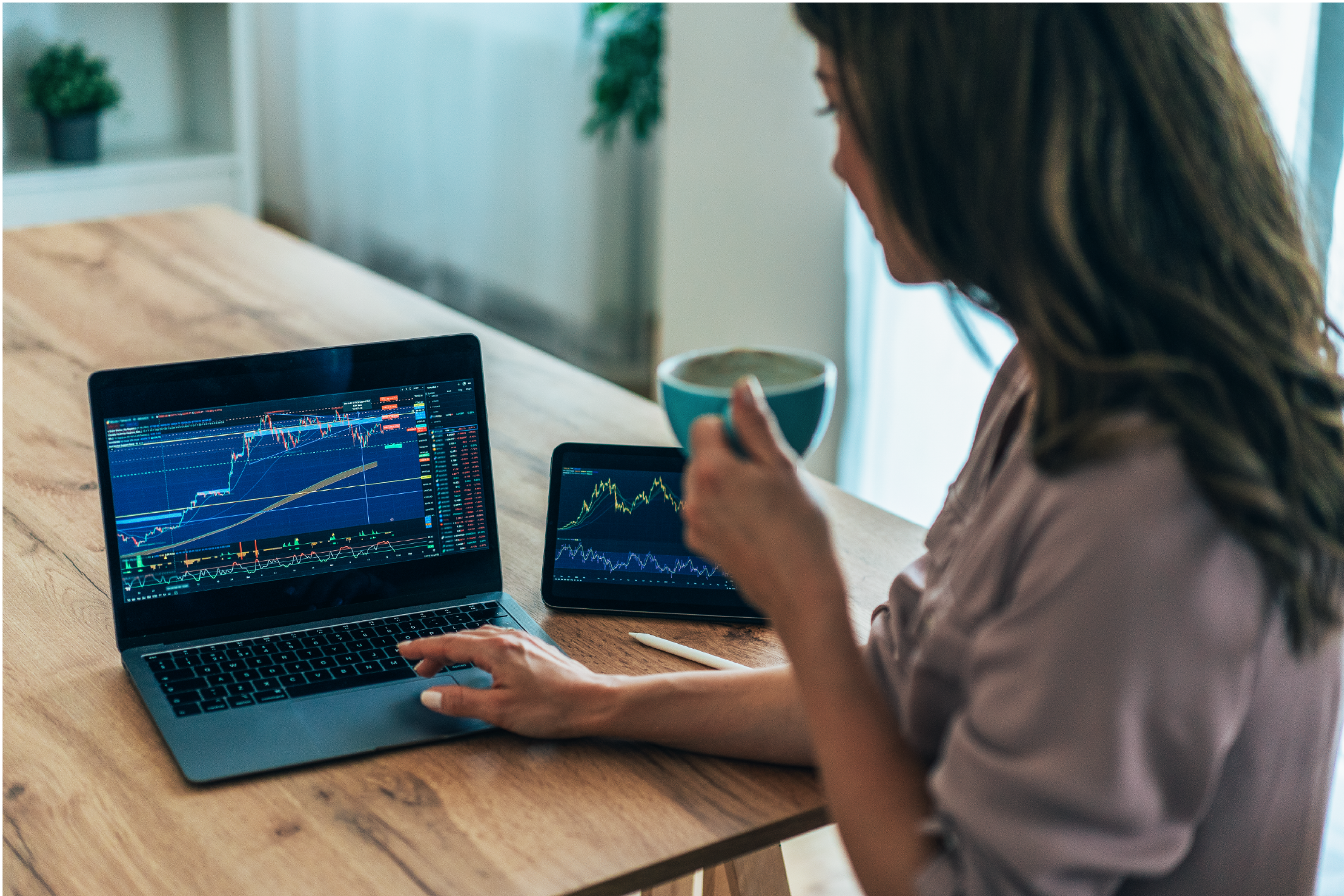 Woman analyzing financial charts on a laptop and a tablet