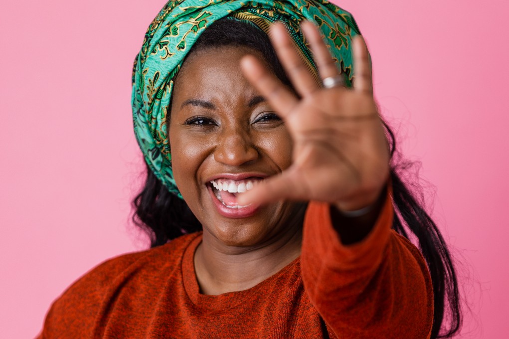A smiling woman showing stop with her hand.