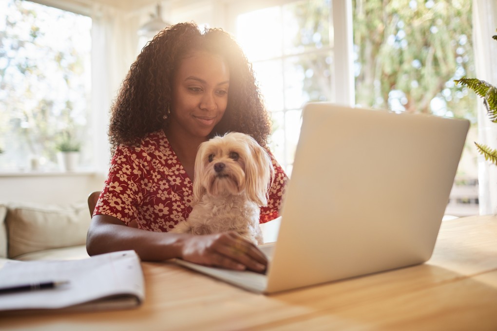 Women smiling in front of her computer with dog on her lap