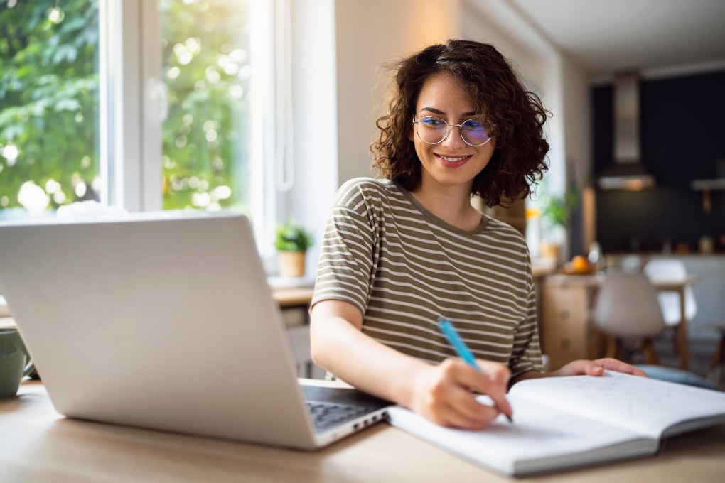 A smiling young woman using her computer to learn about ETFs 