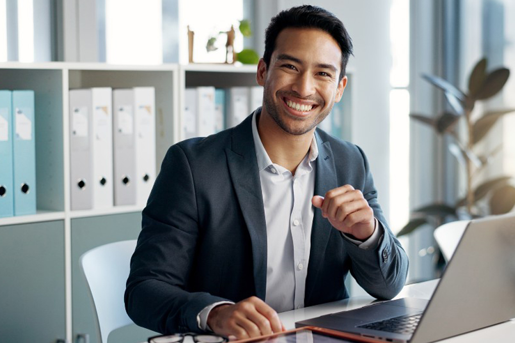 A smiling man investing in index funds and ETFs using his computer.