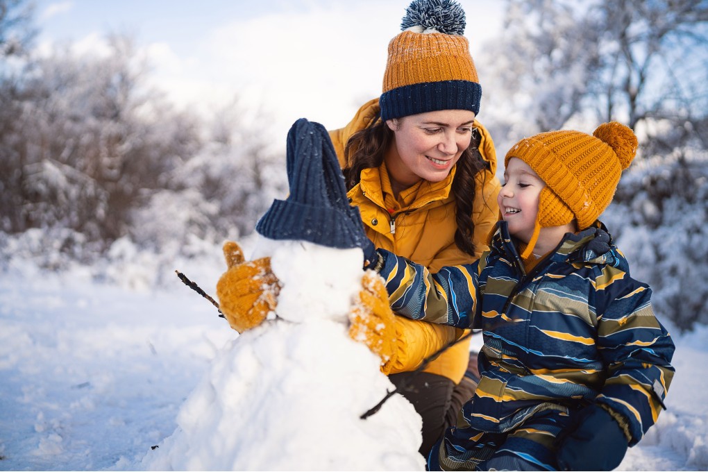 A mother and her son building a snowman during the moth of January.