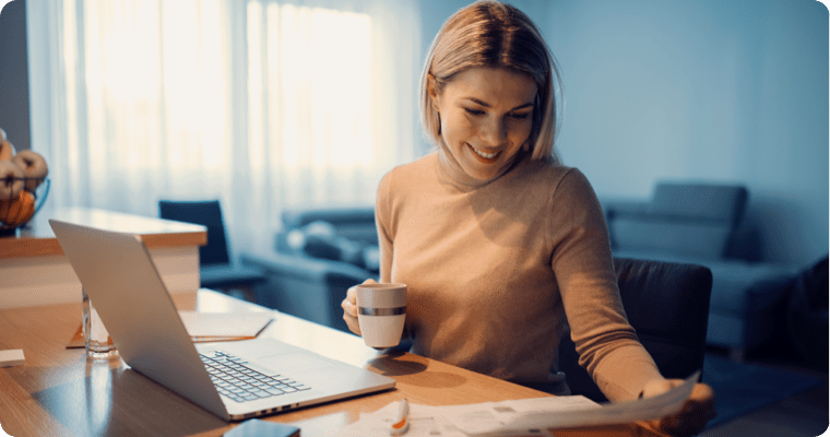 Photo of a woman looking at documents while drinking a coffee in their living room 