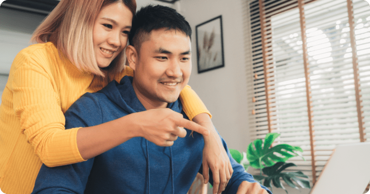 Photo of a smiling couple looking at a laptop together