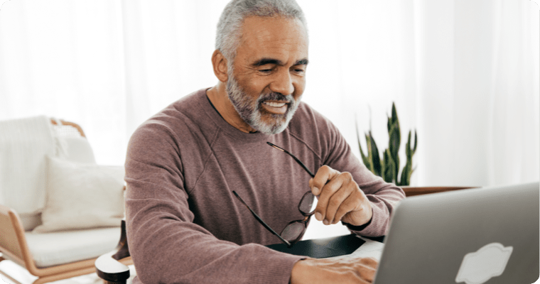 Photo of a smiling man sitting in front of their laptop